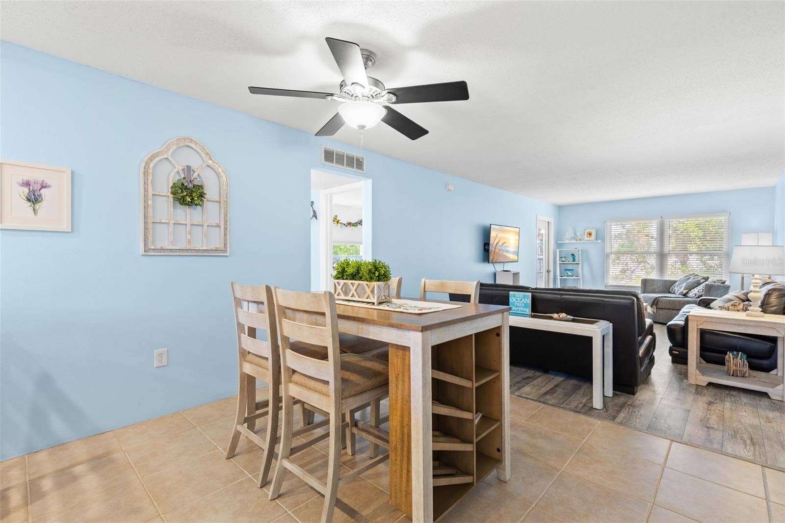 12760 INDIAN ROCKS ROAD, #107, Largo, FL 33774 A second view of the dining area shows how naturally it opens into the living room, with tile flooring transitioning to luxury vinyl and a wide bank of windows bringing light into the far end of the space.