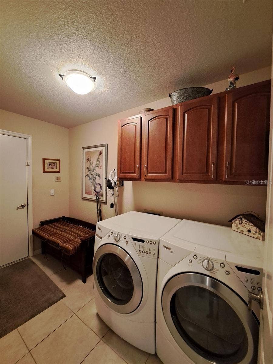 5316 LOCHMEAD TERRACE, Zephyrhills, FL 33541 Laundry with extra space and wood cabinets and entry door to garage