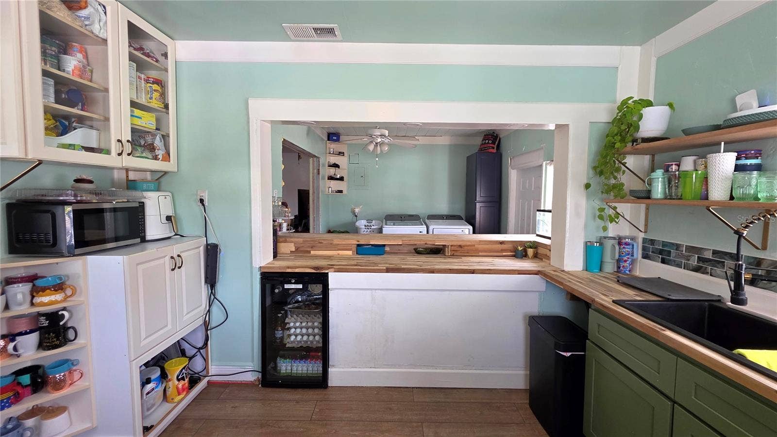 1702 26TH STREET W, Bradenton, FL 34205 Kitchen Pass Through area to Breakfast Bar Seating, with Butcher Block Countertops, Stainless appliances, Decorative Shelving, 2 Windows, and Laminate Flooring