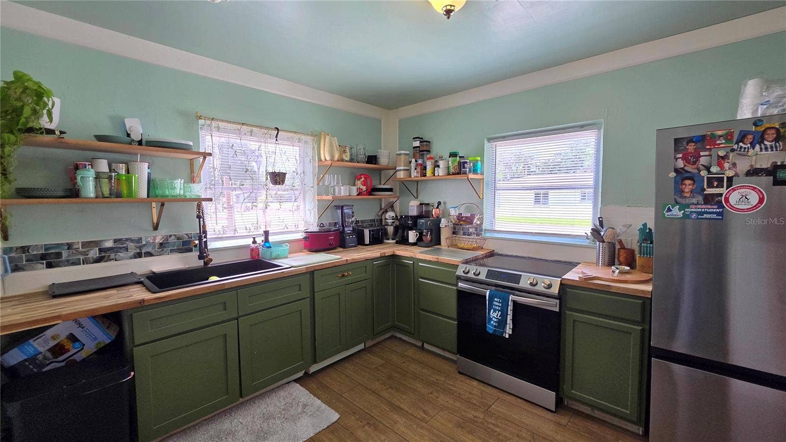 1702 26TH STREET W, Bradenton, FL 34205 Kitchen with Butcher Block Countertops, Stainless appliances, Undermount Sink, Decorative Shelving, 2 Windows, and Laminate Flooring