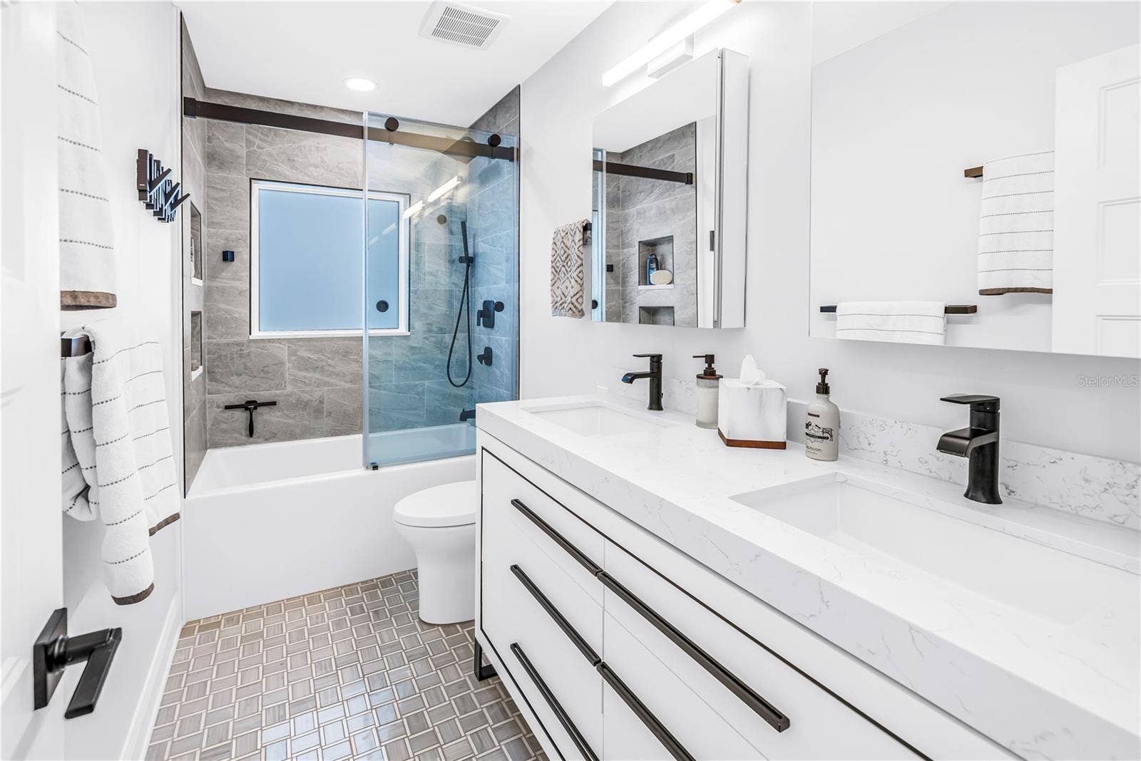 1114 2ND AVENUE S, Tierra Verde, FL 33715 2nd bath with deep soaking tub, custom dual vanity with European style drawers, stone countertops, 2 Robern medicine cabinets, frosted glass window for natural light and comfort height European style flush toilet.