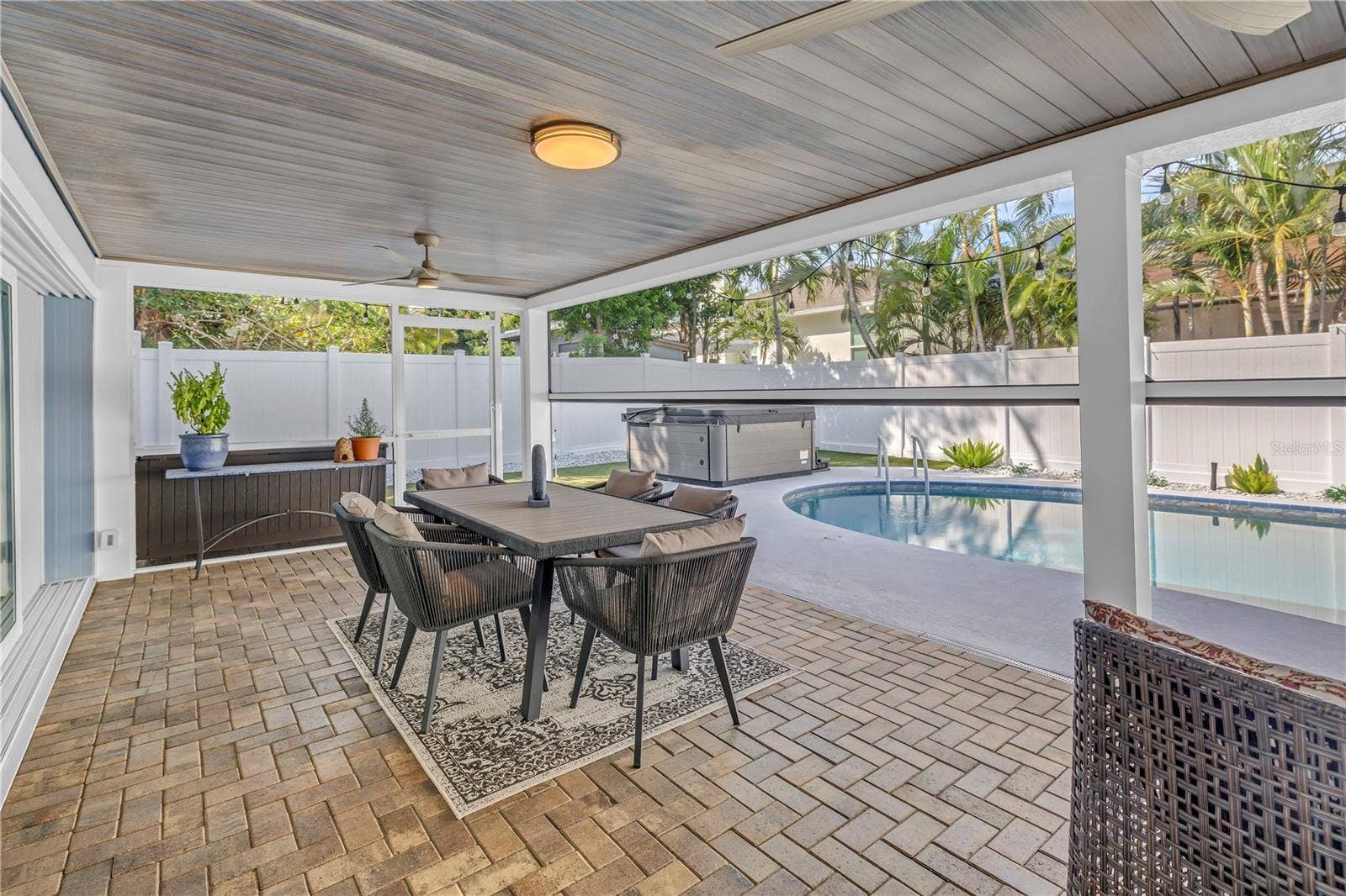 1114 2ND AVENUE S, Tierra Verde, FL 33715 Paved patio with bead board ceiling for your outdoor Dining room with pool and HOT TUB beyond. Remote screens at half mast!