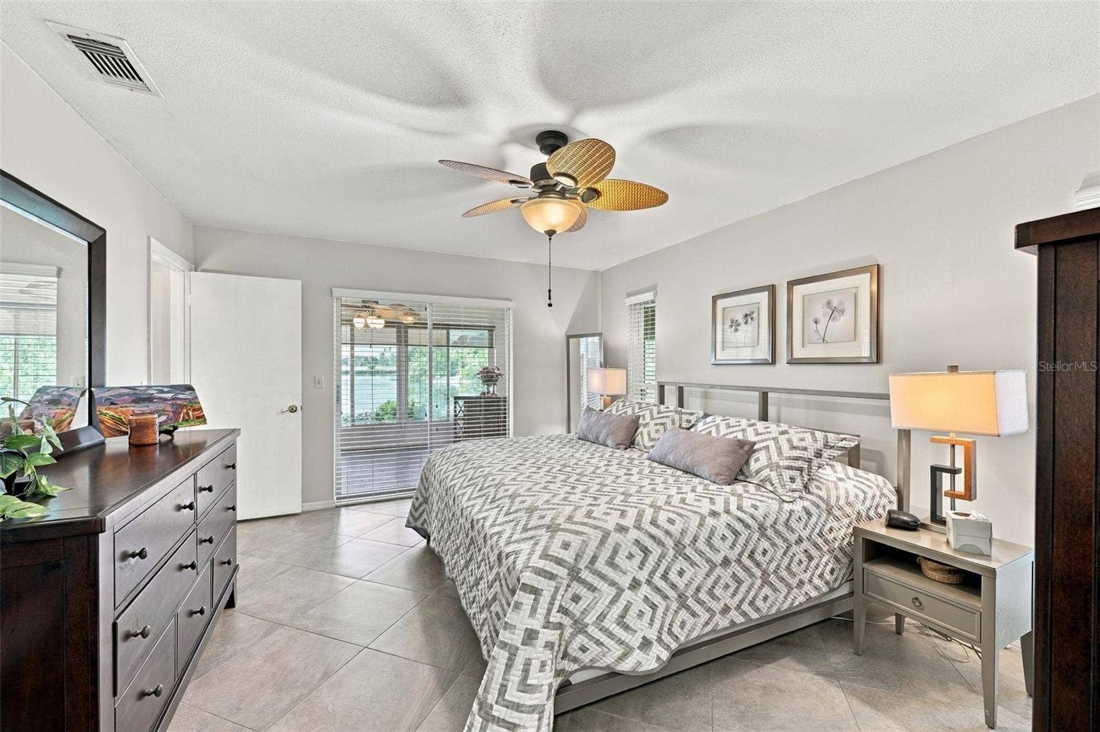 211 STONEHAM DRIVE, Sun City Center, FL 33573 Primary bedroom is large, bright and relacing. Notice the consistent flooring throughout the home. Large beautiful sliding glass doors allow natural Florida sunshine to filter into the room with a view of the water.
