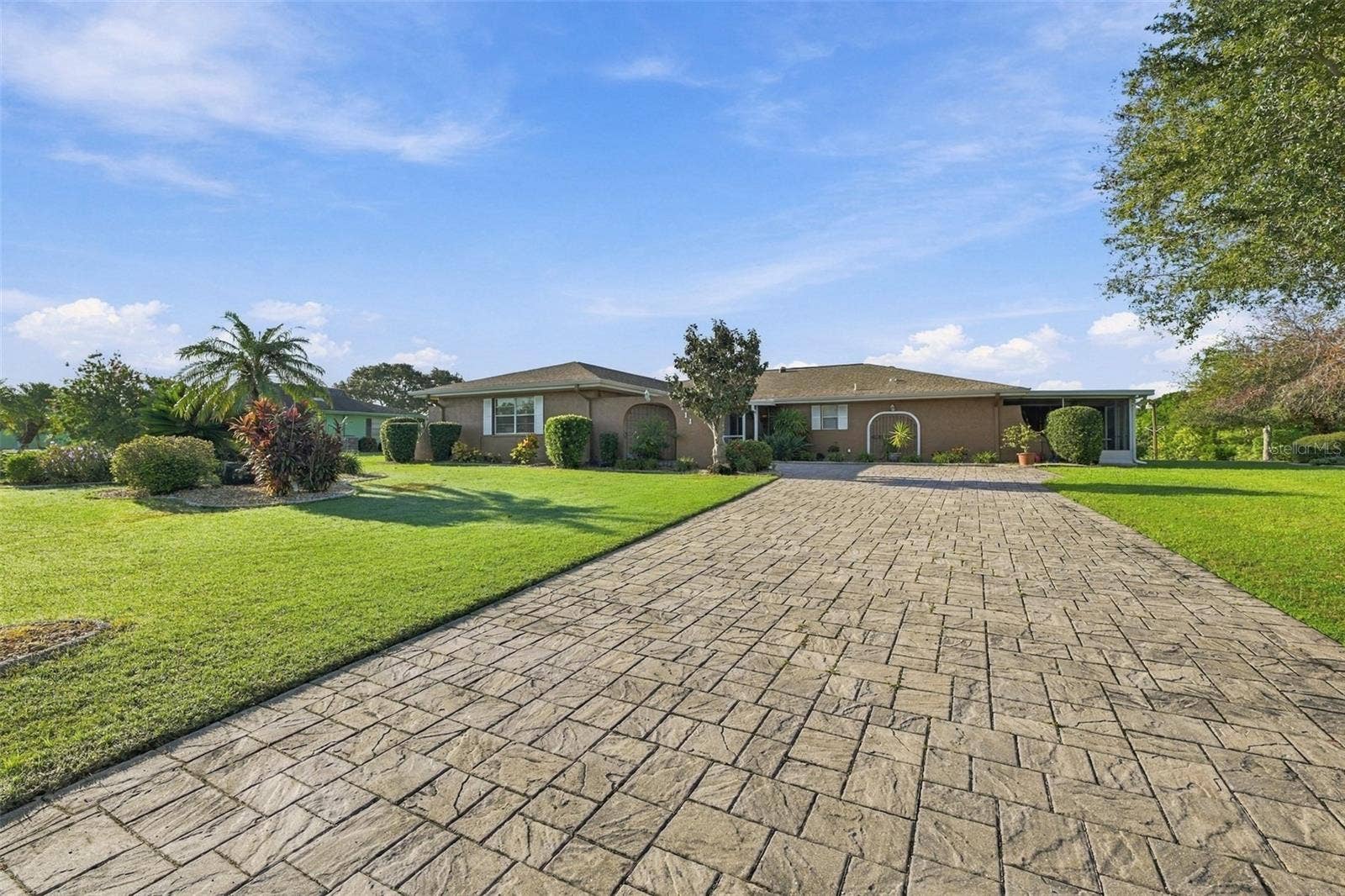 211 STONEHAM DRIVE, Sun City Center, FL 33573 Beautiful manicured landscaping and custom pavered driveway, which is long and wide for multiple vehicles.