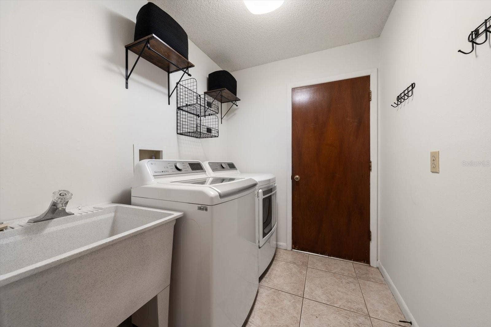 1105 DEER RUN PLACE, Valrico, FL 33594 Update laundry room with sink and shelving and access to the large garaage with tiled flooring and a workshop area.