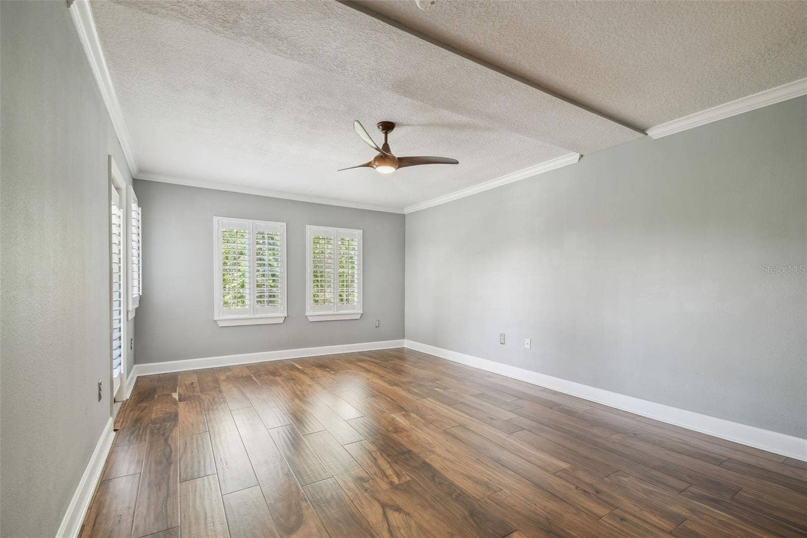 Spacious primary suite with a door leading out to the enclosed balcony.
