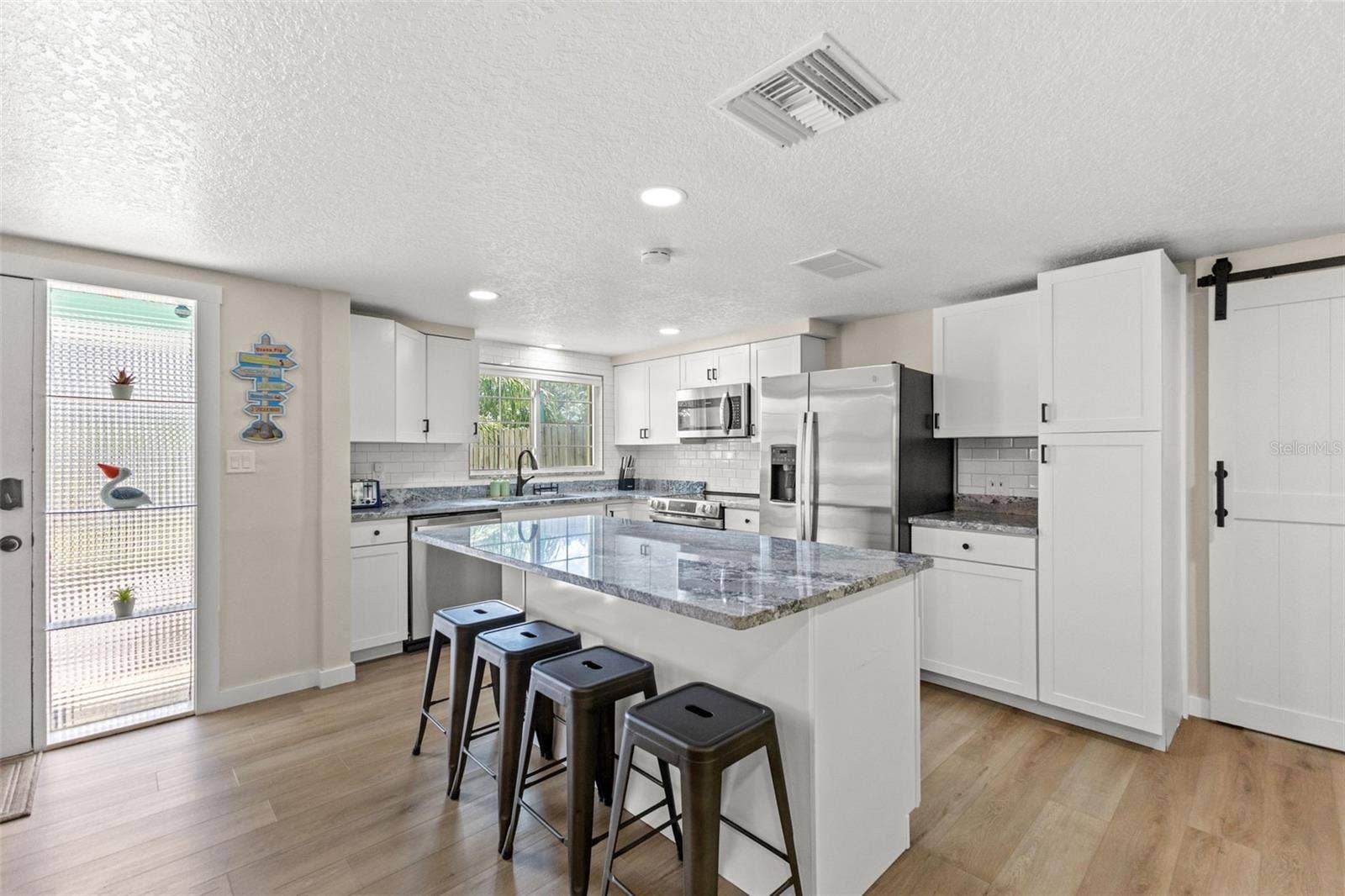 201 SOUTH STREET, Palm Harbor, FL 34683 Bright, renovated kitchen with a large center island, seating for four, stainless steel appliances, and plenty of cabinet storage.