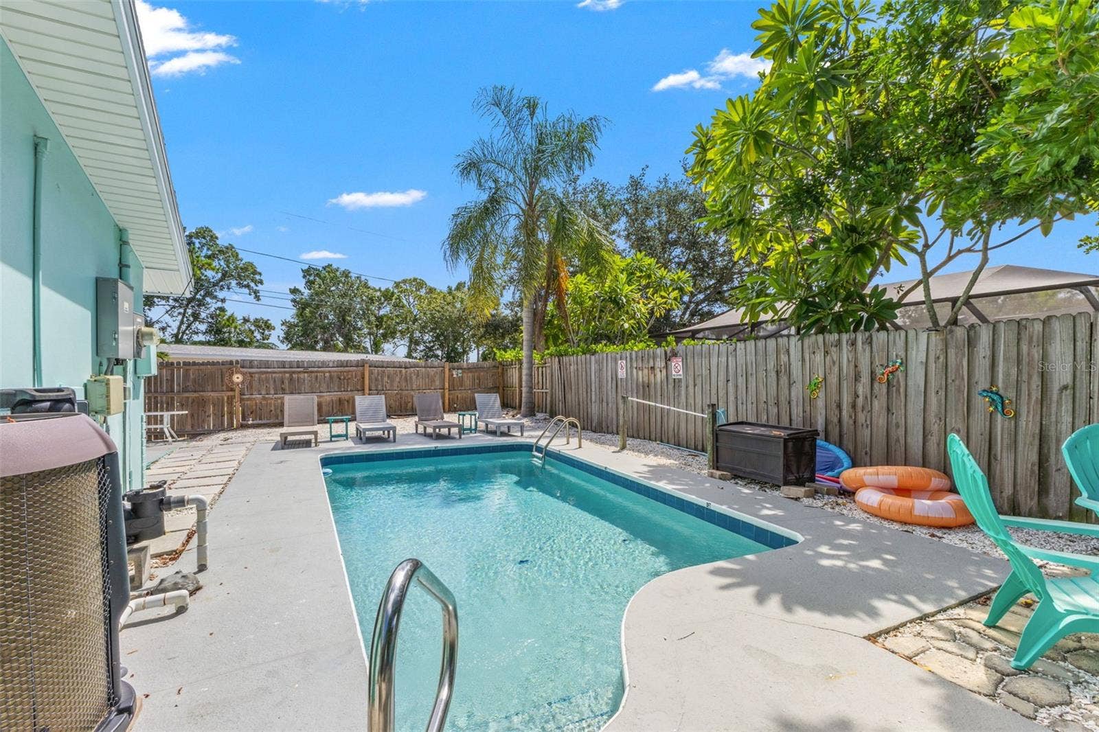 201 SOUTH STREET, Palm Harbor, FL 34683 Private heated pool surrounded by multiple areas for lounging and outdoor entertaining, with a new pool pump and heater added in 2025.