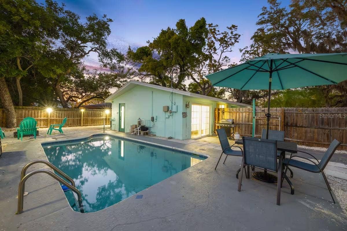 201 SOUTH STREET, Palm Harbor, FL 34683 Evening lighting shows off the backyards resort-like setup, complete with heated pool, outdoor dining, BBQ area, and space to gather around the fire pit.