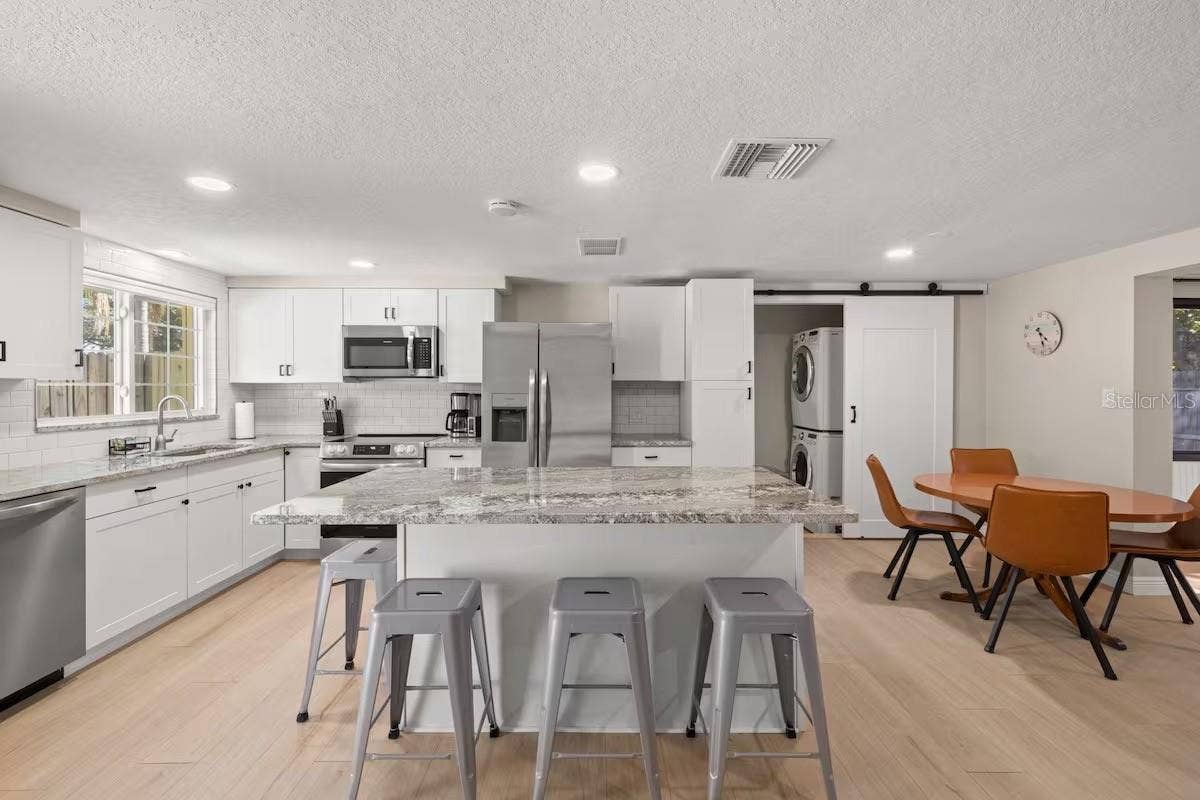 201 SOUTH STREET, Palm Harbor, FL 34683 Another view highlights the generous island, open dining area, and convenient tucked-away laundryall seamlessly connected to the main living spaces.