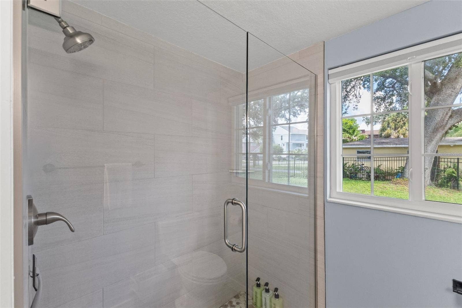 201 SOUTH STREET, Palm Harbor, FL 34683 Updated bathroom features a glass-enclosed walk-in shower with large-format tile and pebble-style shower flooring.