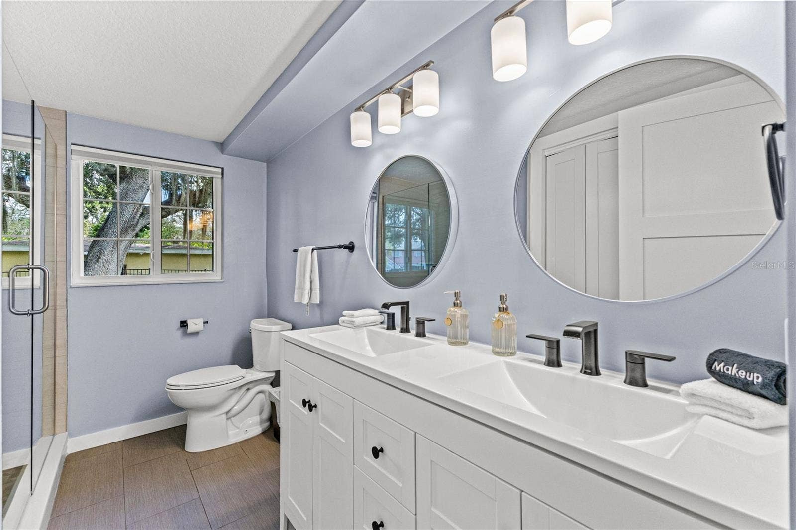201 SOUTH STREET, Palm Harbor, FL 34683 Updated bathroom with dual sinks, modern fixtures, generous vanity storage, and a glass-enclosed walk-in shower.