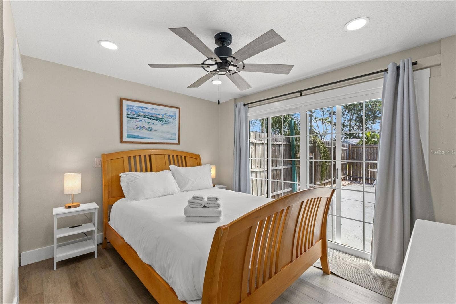 201 SOUTH STREET, Palm Harbor, FL 34683 Owner's edroom with luxury vinyl plank flooring, ceiling fan, and sliding glass doors opening directly to the pool area.