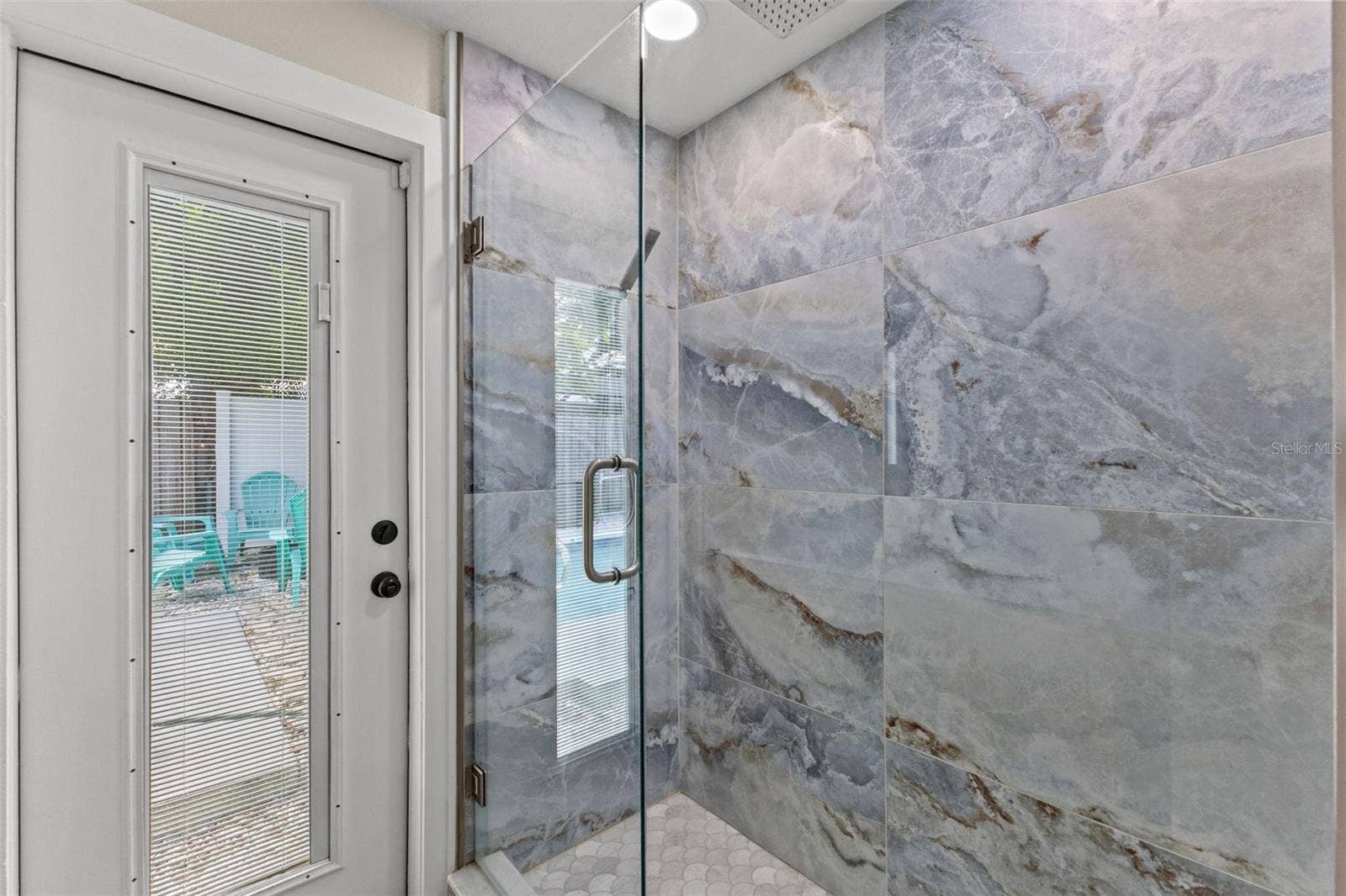 201 SOUTH STREET, Palm Harbor, FL 34683 Beautifully tiled walk-in shower with frameless glass enclosure, oversized tile, and a rainfall-style showerhead.