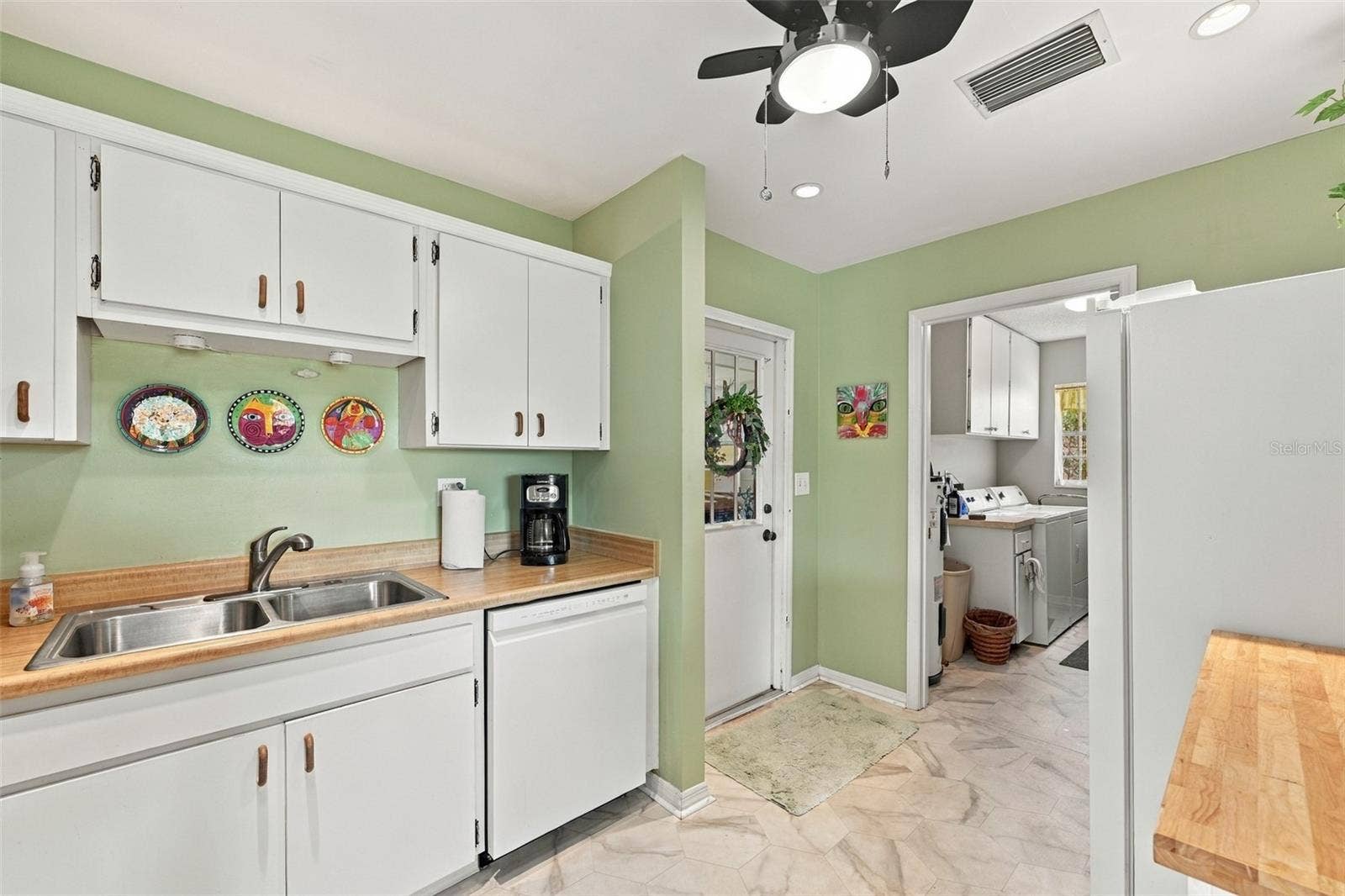 Simple all white cabinetry gives this room a sparkling clean appearance with bright recessed lights and a ceiling fan.