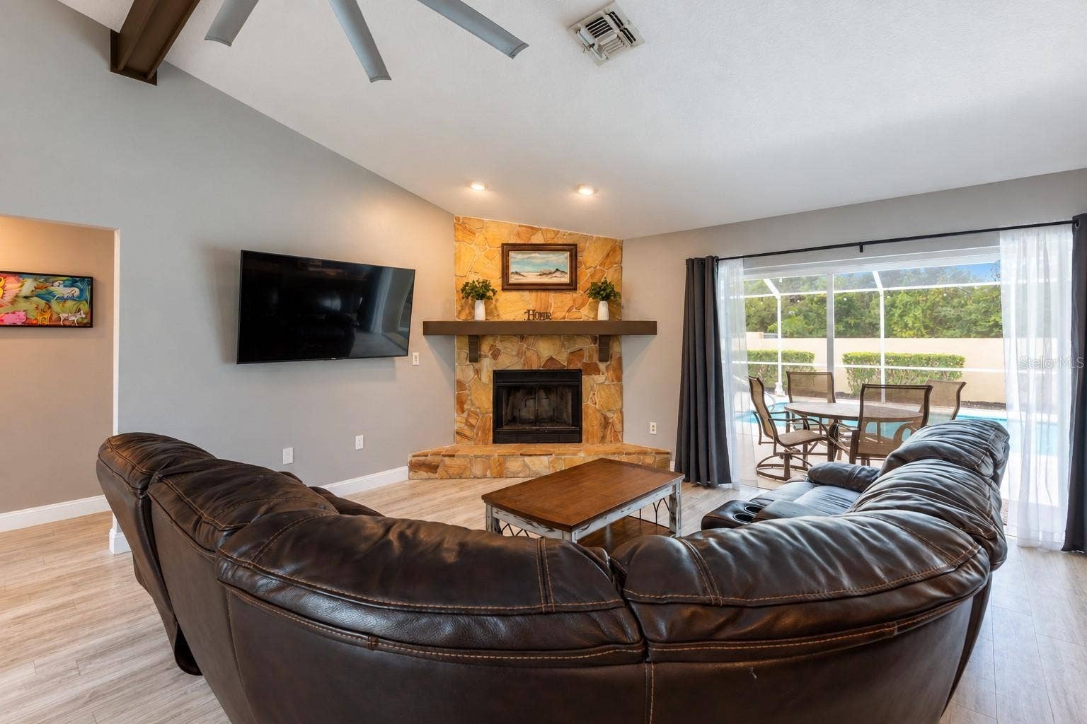 9713 LOMALINDA COURT, New Port Richey, FL 34655 Great room with a wood burning fireplace and the sliding doors are recessed open to bring the inside and outside together.