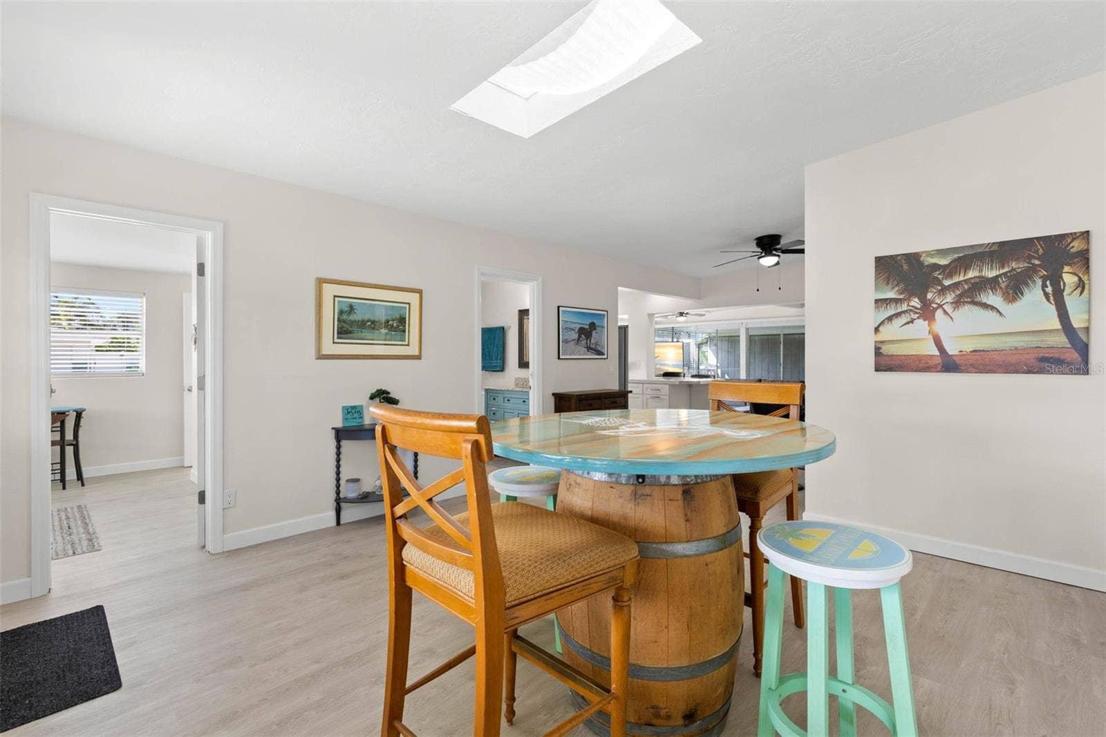 The spacious dining area is filled with natural light from the skylight and flows easily into the adjoining kitchen and living spaces, with 2025 luxury vinyl plank flooring creating a clean, cohesive look.
