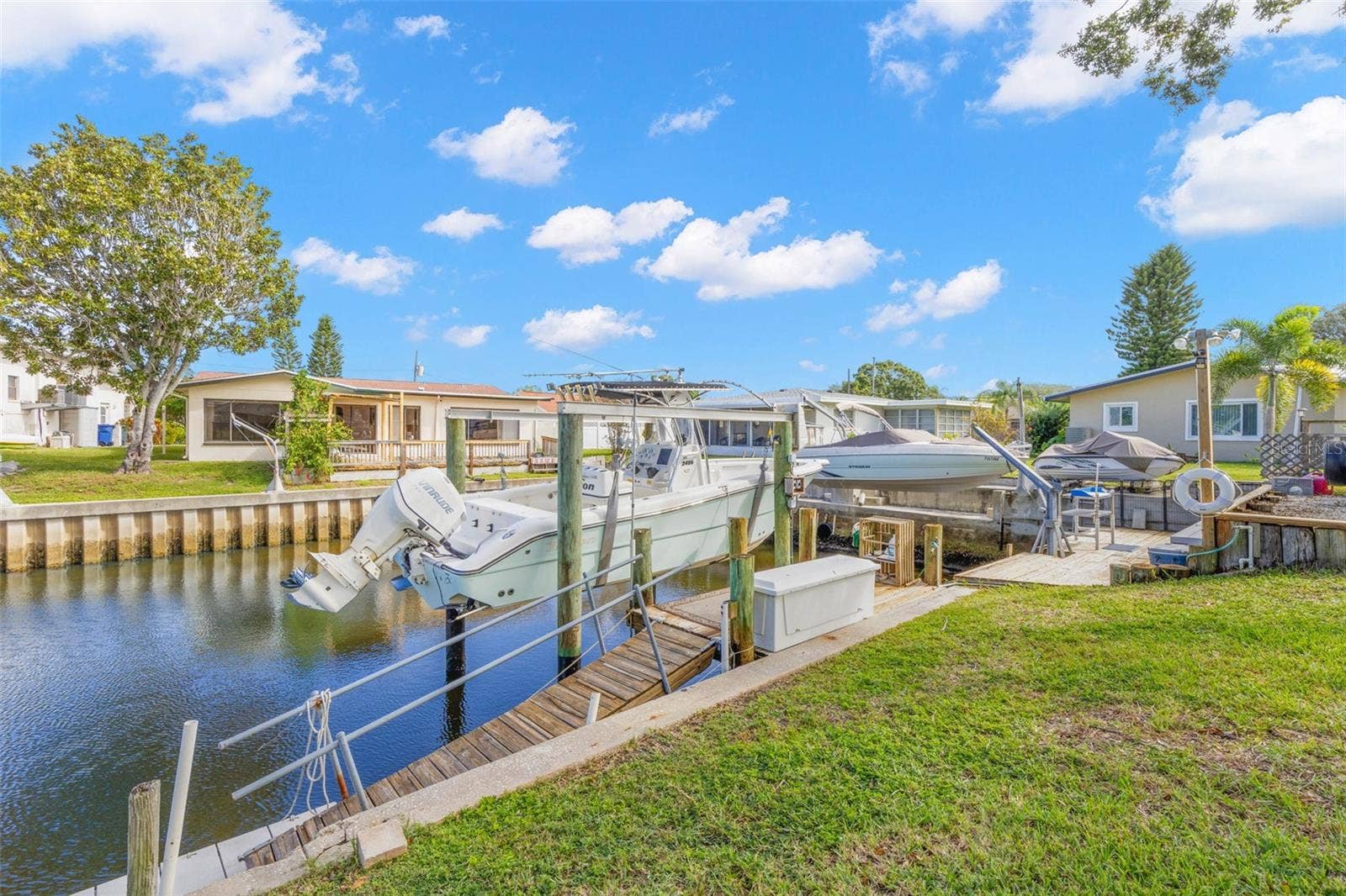 The canal frontage is equipped for easy days on the water, with a 10,000-pound boat lift, wooden dock, railed access walkway, waterside storage, and approximately 60 feet of seawall, all just steps from the backyard.