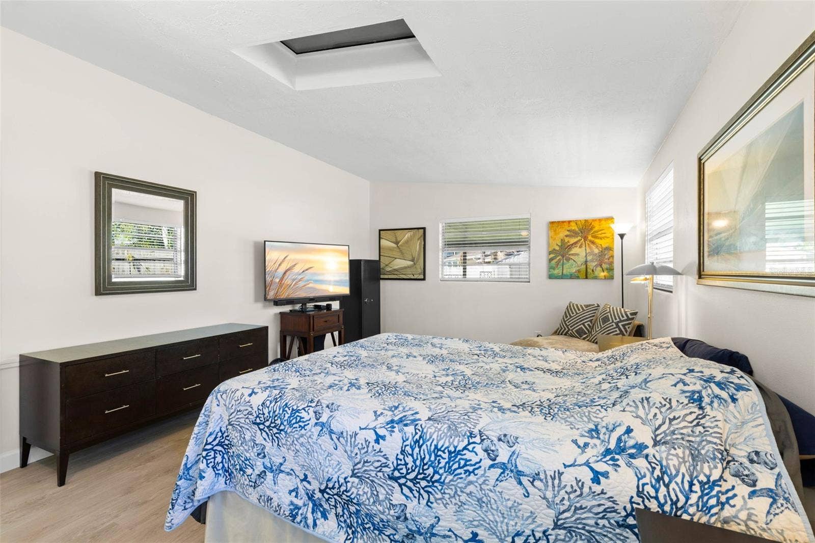 The primary bedroom offers exceptional space for both sleeping and lounging, with multiple windows, a skylight, neutral tones, and luxury vinyl plank flooring (2025) keeping the room bright and cohesive.