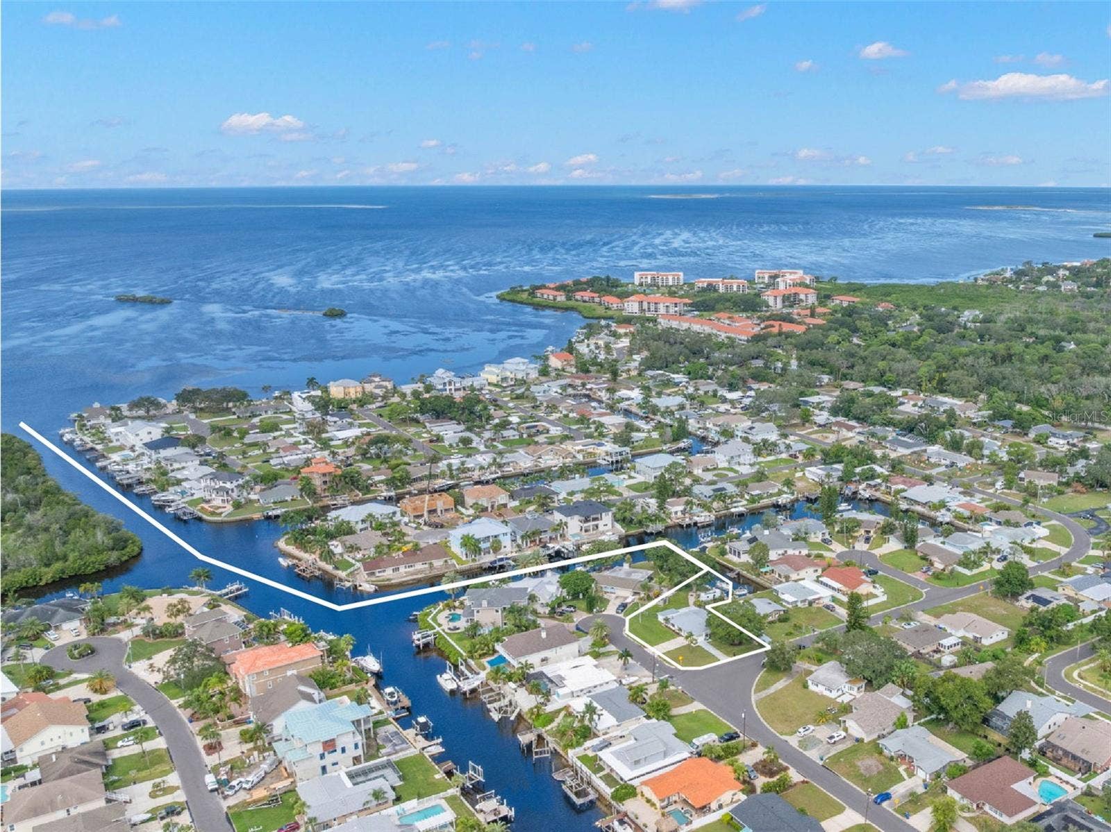 A sweeping aerial view puts the waterfront setting in perspective, showing Baywood Villages canal system winding toward the open Gulf of Mexico  a standout location for boaters who want direct saltwater access close to home.
