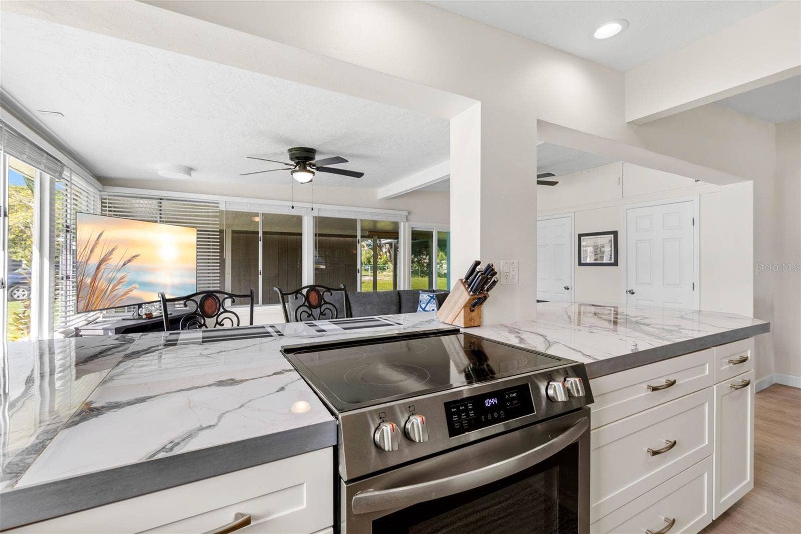 The updated kitchen (2025) showcases dramatic stone-look countertops, white Shaker-style cabinetry, stainless steel appliances, recessed lighting, and generous drawer storage, with an open design that keeps the cook connected to the adjoining living space.
