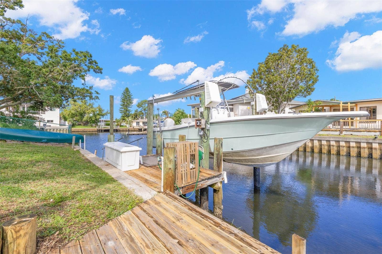 The waterfront setup is ready for serious boating, with a substantial wooden dock, 10,000-pound boat lift with davits, waterside storage, and a convenient water connectionall directly on the canal with access toward the Gulf.