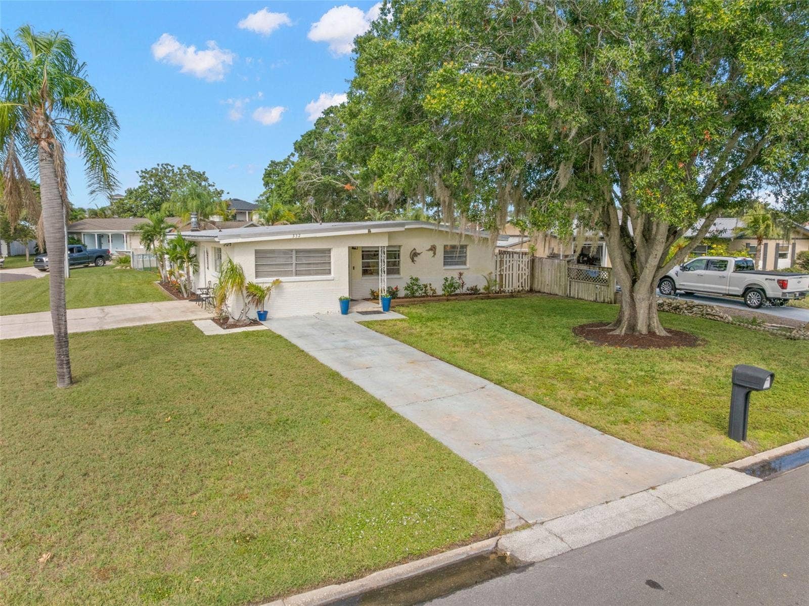 An elevated view highlights the homes generous 11,800-square-foot corner setting, with a broad lawn, long driveway, mature shade trees, and the extra breathing room created by the one-and-a-half-lot property.
