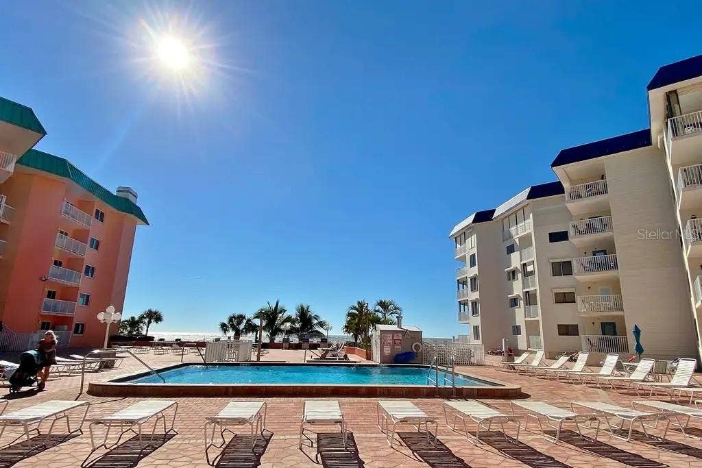 18400 GULF BOULEVARD, #1208, Indian Shores, FL 33785 RESORT-STYLE POOL DECK COMPLETE WITH LOUNGE CHAIRS, TABLES AND UMBRELLAS FOR GUEST USE AND RELAXATION