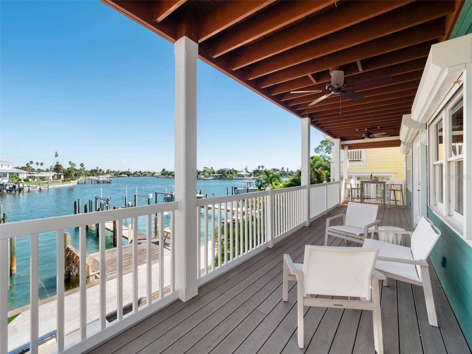 Main floor covered outdoor deck with staircase to pool deck