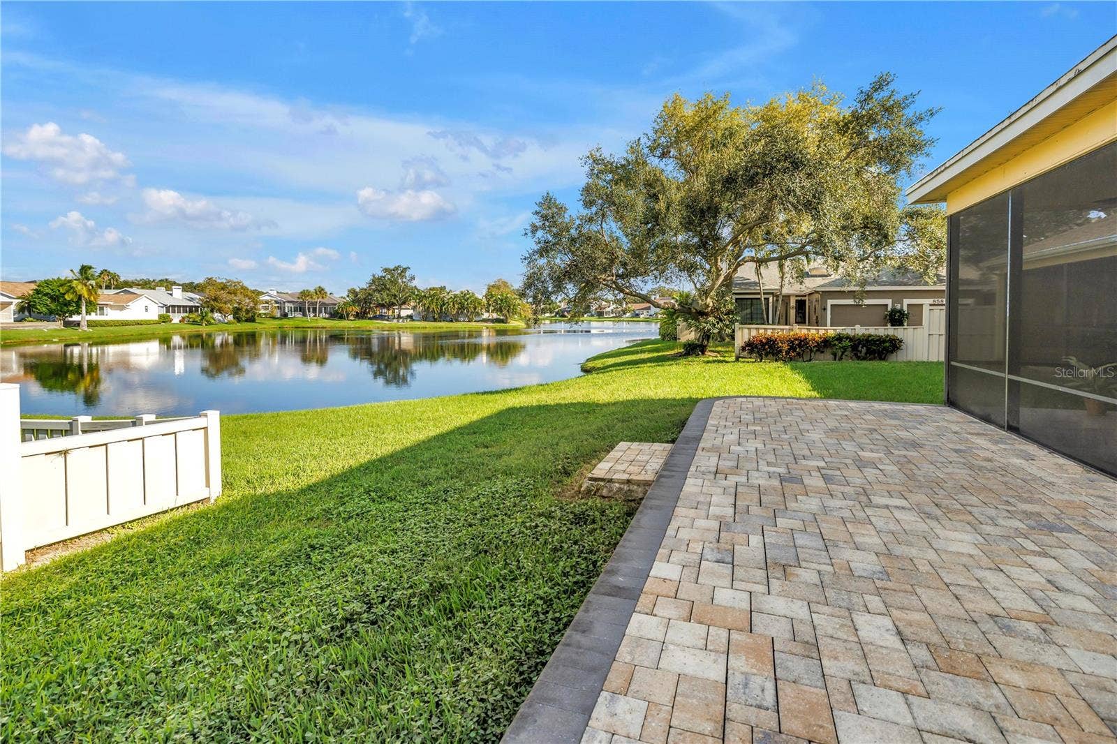 868 GLADES COURT NE, St Petersburg, FL 33702 The elevated paver patio at the rear of the property overlooks a scenic grassy knoll and provides an expansive view of the lake, which serves as a natural habitat for various tropical birds.