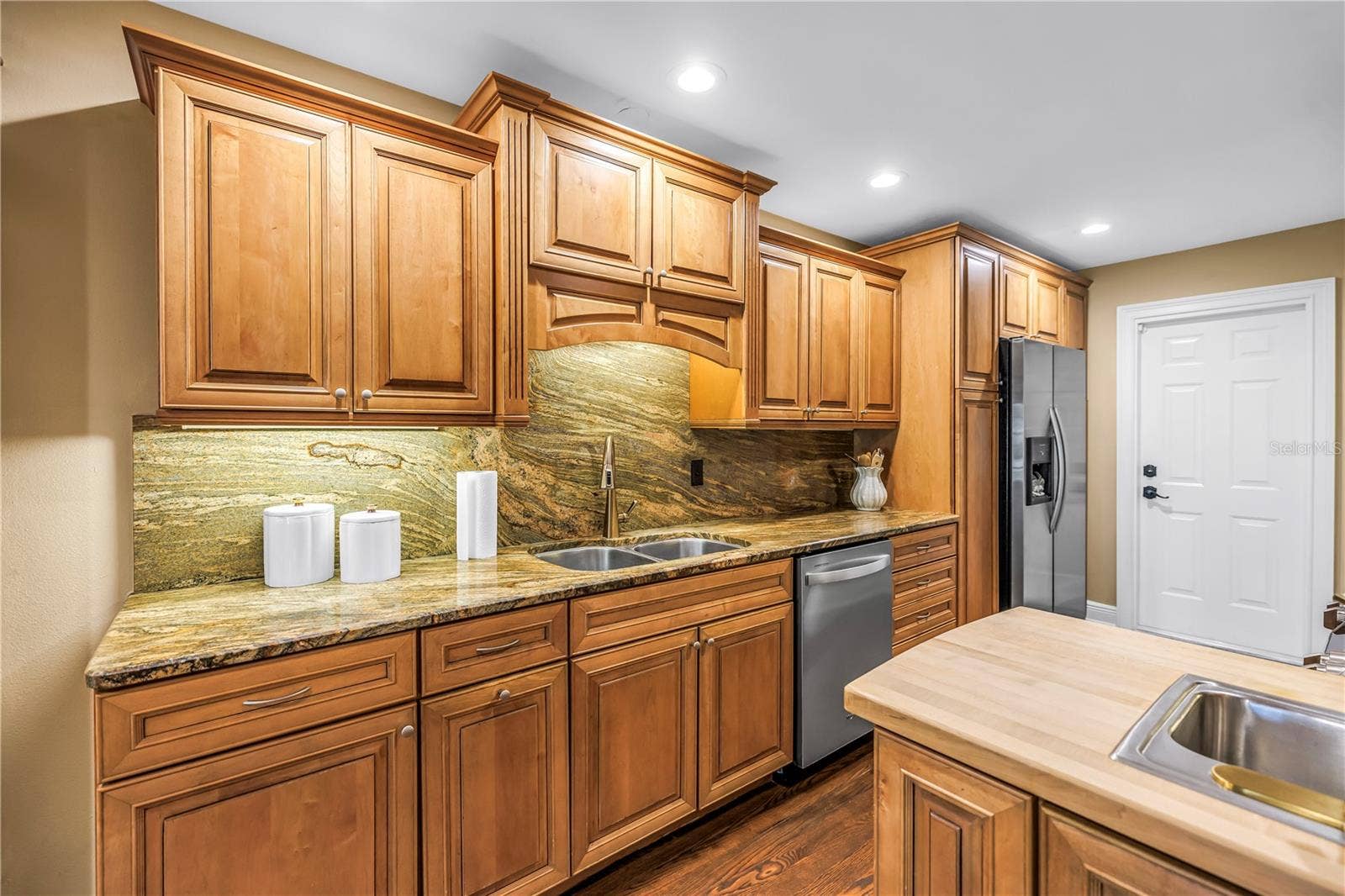 868 GLADES COURT NE, St Petersburg, FL 33702 This custom kitchen features solid wood cabinetry, granite countertops, and a matching backsplash. It is equipped with updated stainless steel appliances, a chopping block island, and an integrated prep sink. An ideal space for any culinary enthusiast.