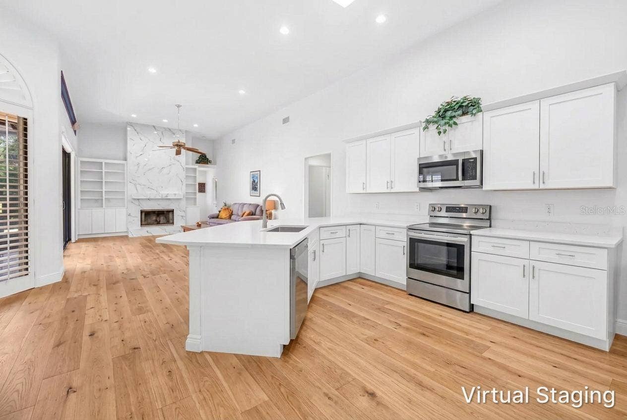 1186 GASPARILLA DRIVE NE, St Petersburg, FL 33702 Virtual Rendering of previous photo with updated cabinetry, flooring, fireplace and removal of soffit and hanging upper cabinetry.
