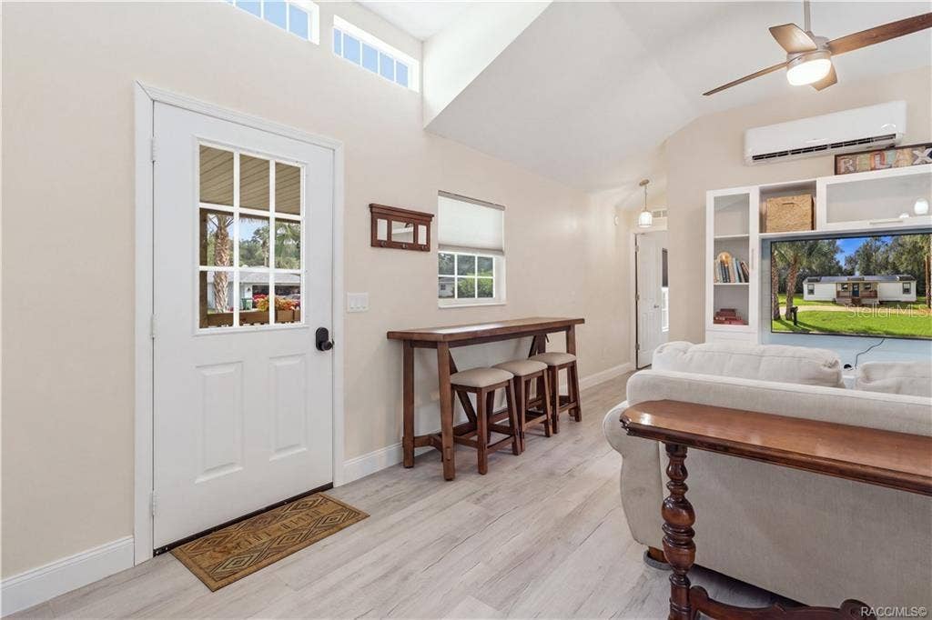 6230 W GLEN ROBBIN COURT, Crystal River, FL 34429 Living Area & Front Entry Welcoming living space featuring VAULTED CEILINGS, high transom windows, ceiling fan, attractive flooring & a convenient seating area near the front entrance.
