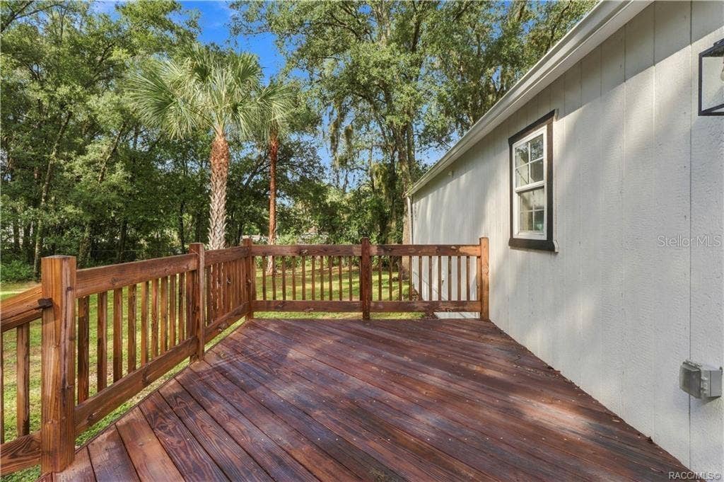 6230 W GLEN ROBBIN COURT, Crystal River, FL 34429 Rear Deck Spacious wooden deck featuring sturdy railings & room for outdoor seating, surrounded by Florida greenery & mature palms.