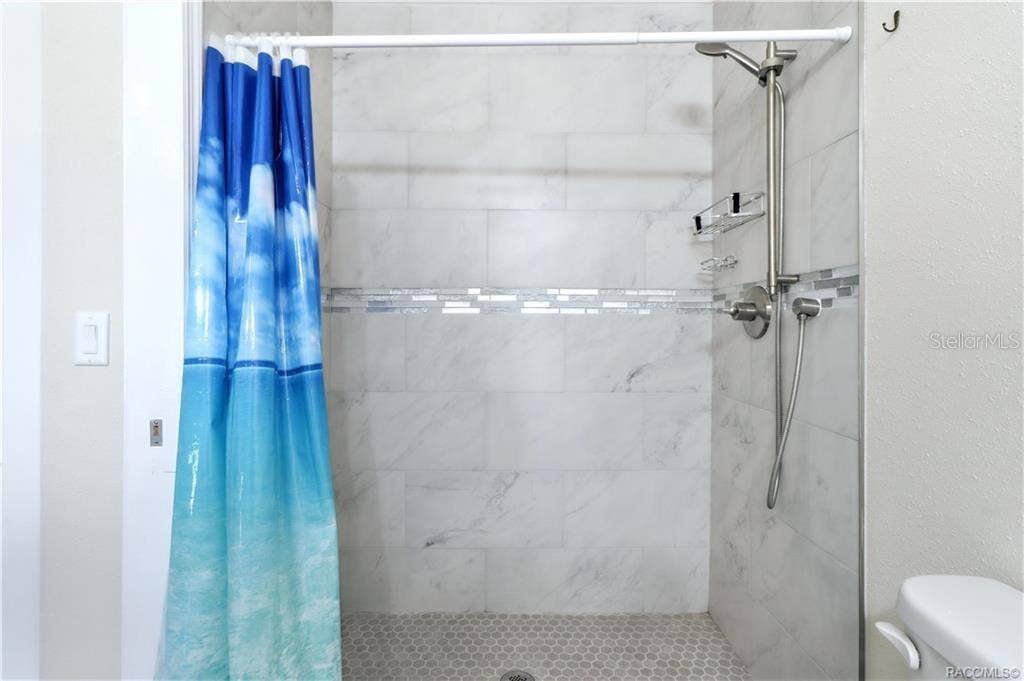 6230 W GLEN ROBBIN COURT, Crystal River, FL 34429 Primary Bathroom Shower Beautifully tiled WALK-IN SHOWER featuring marble-look wall tile, decorative mosaic accent & handheld showerhead.