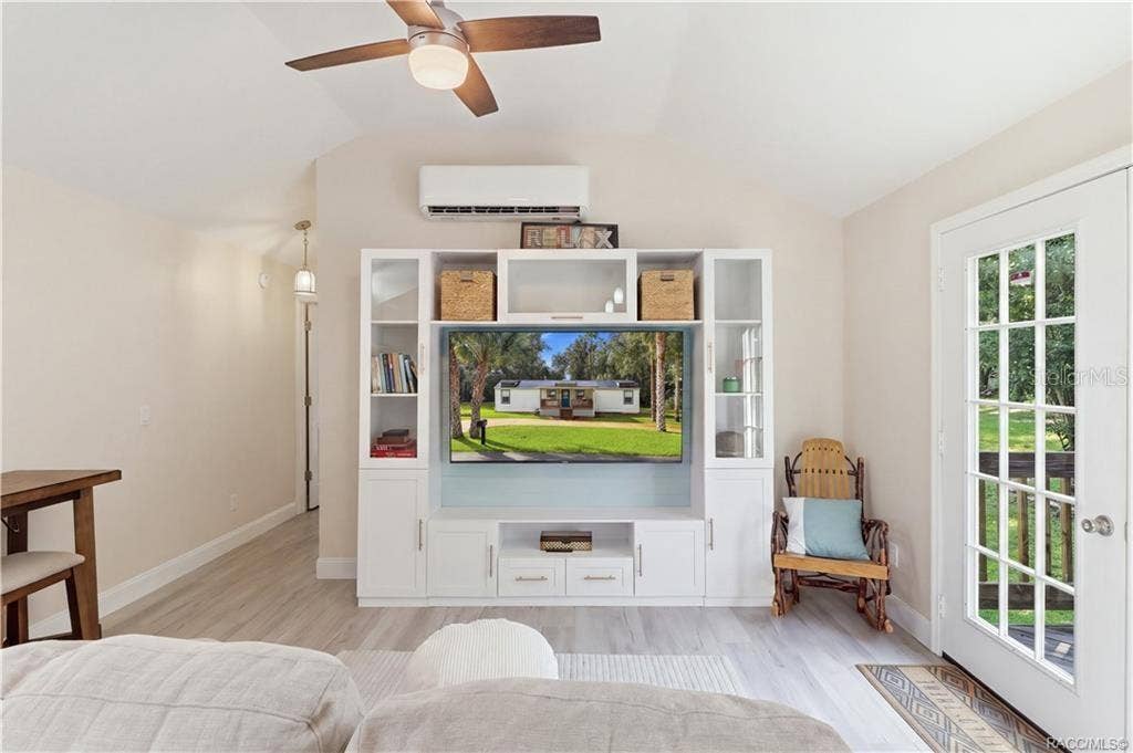 6230 W GLEN ROBBIN COURT, Crystal River, FL 34429 Living Room Bright & inviting living room featuring VAULTED CEILINGS, luxury vinyl plank flooring, ceiling fan, w/entertainment cabinetry & a MINI-SPLIT HEATING & COOLING SYSTEM. French doors provide views of the backyard & access to the rear deck.
