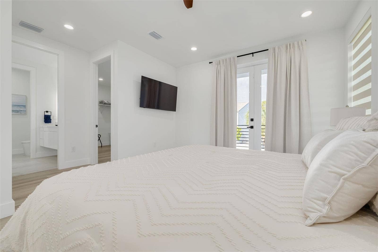 7609 DEEDRA CIRCLE, Port Richey, FL 34668 Bedroom with balcony and an ensuite on the main living floor.