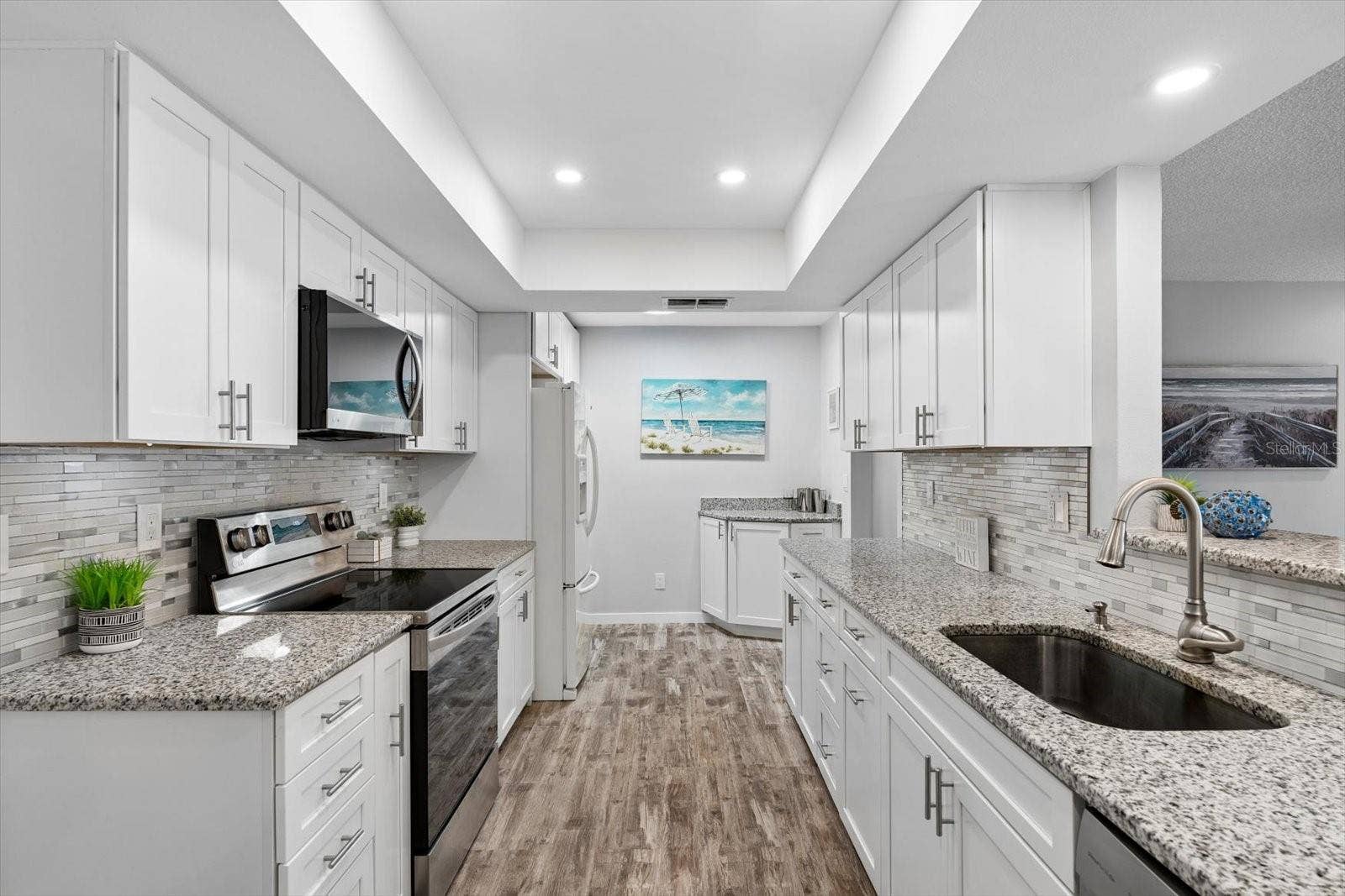 Remodeled kitchen with white shaker cabinets, granite countertops