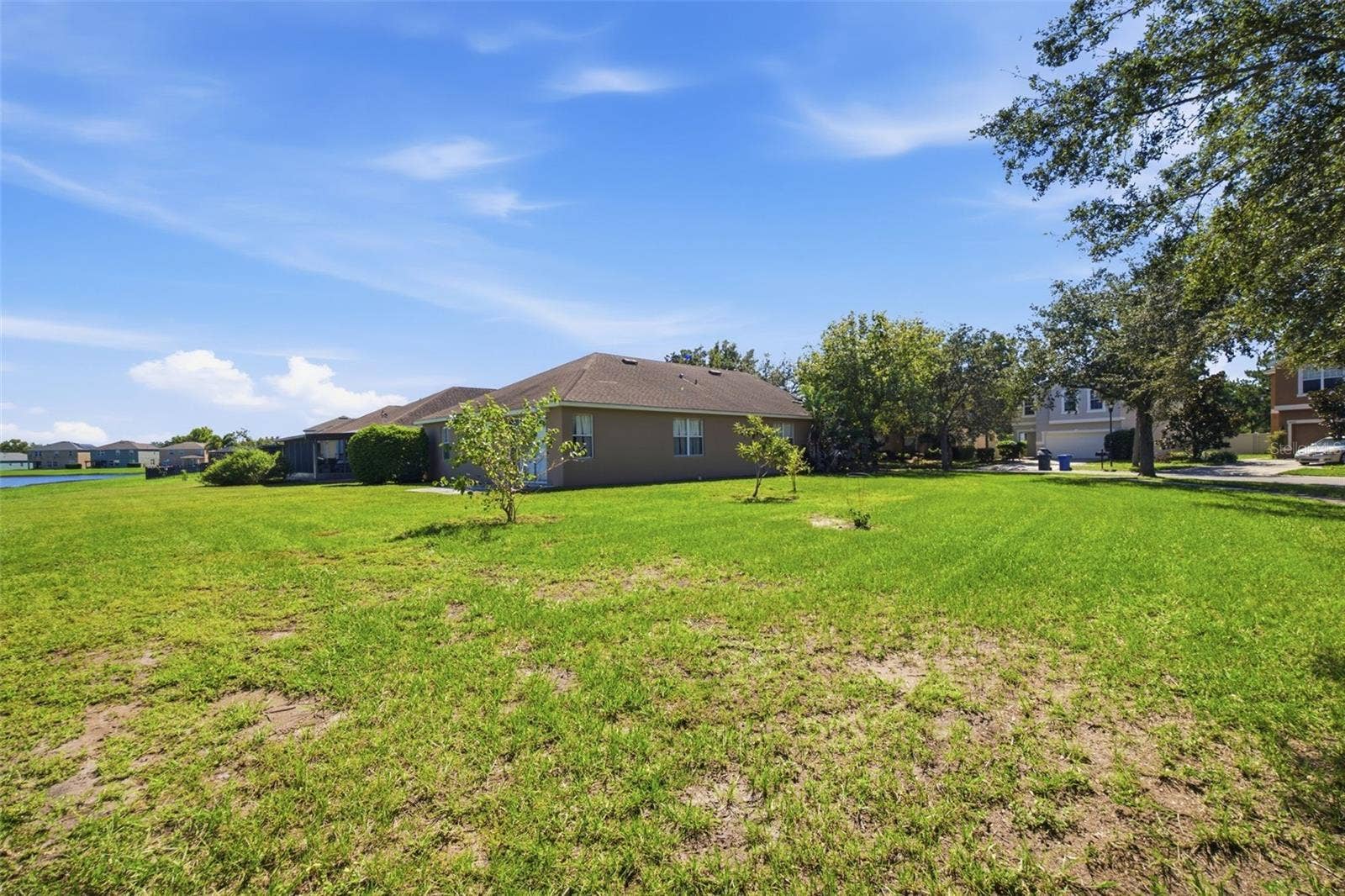 Wide lawn along side of home with pond in the distance
