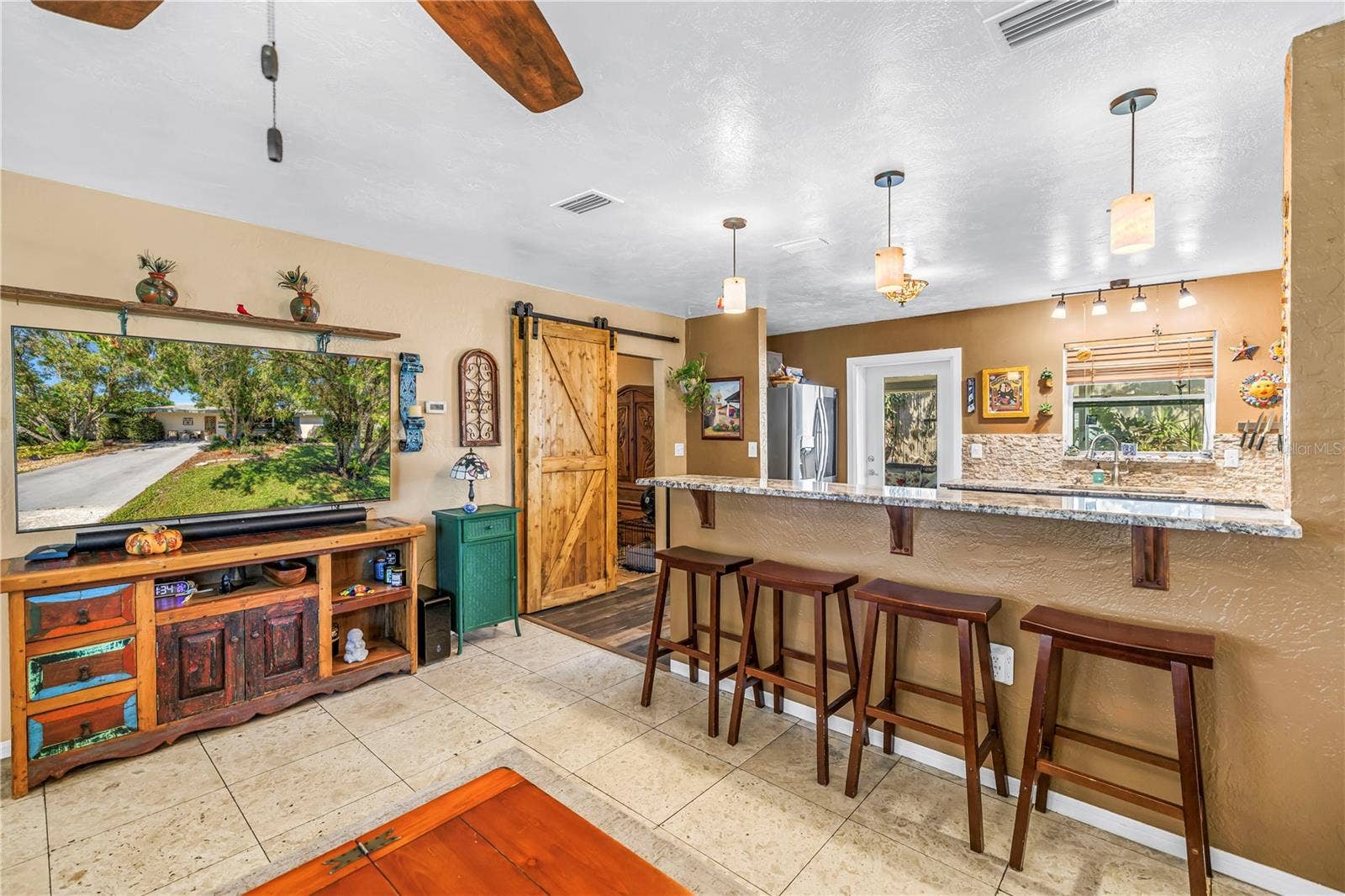 Breakfast bar seating at the kitchen and barn door is to the primary bedroom.