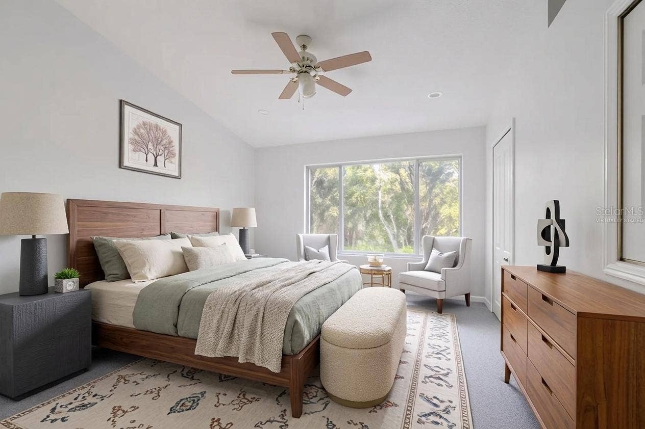 2432 LAKE WOODBERRY CIRCLE, Brandon, FL 33510 The Primary bedroom features neutral tone walls and carpet, a ceiling fan with light kit and vaulted ceiling. (Photo has been virtually staged.)