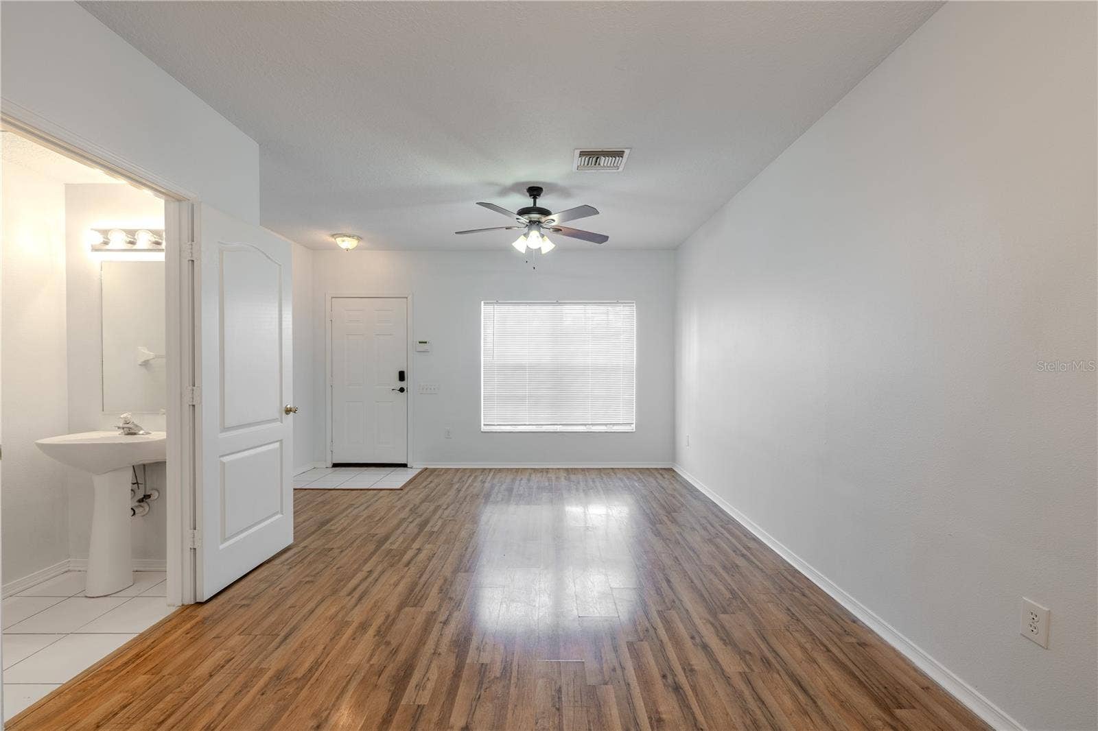 2432 LAKE WOODBERRY CIRCLE, Brandon, FL 33510 The Living room features neutral tones, wood laminate flooring, a ceiling fan with light kit and picture window.