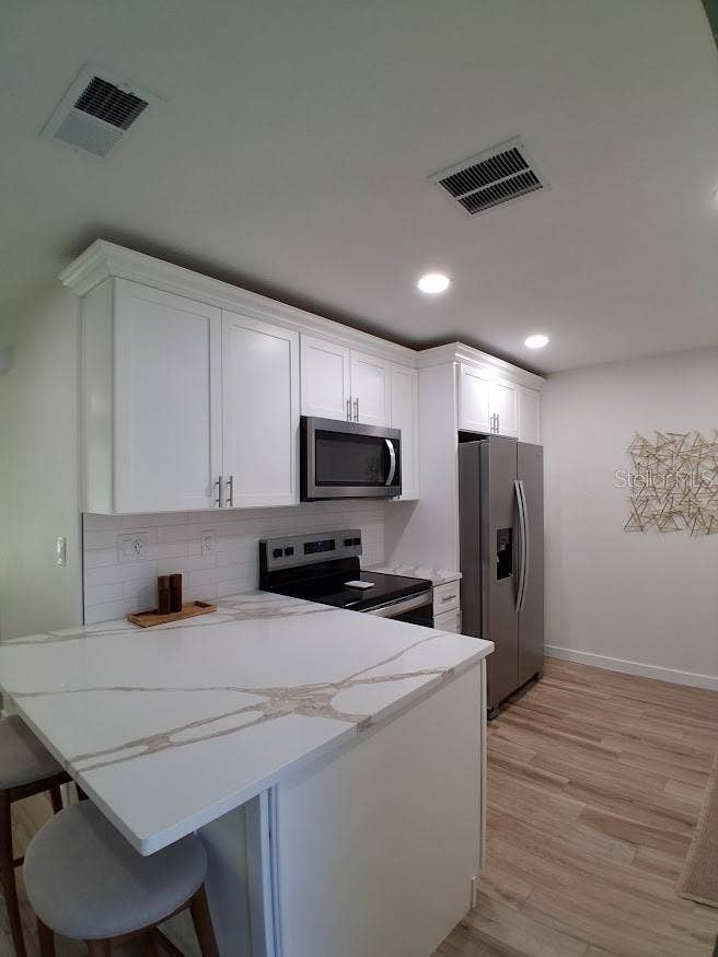 Kitchen, west side (refrigerator, microwave, stove and serving island).