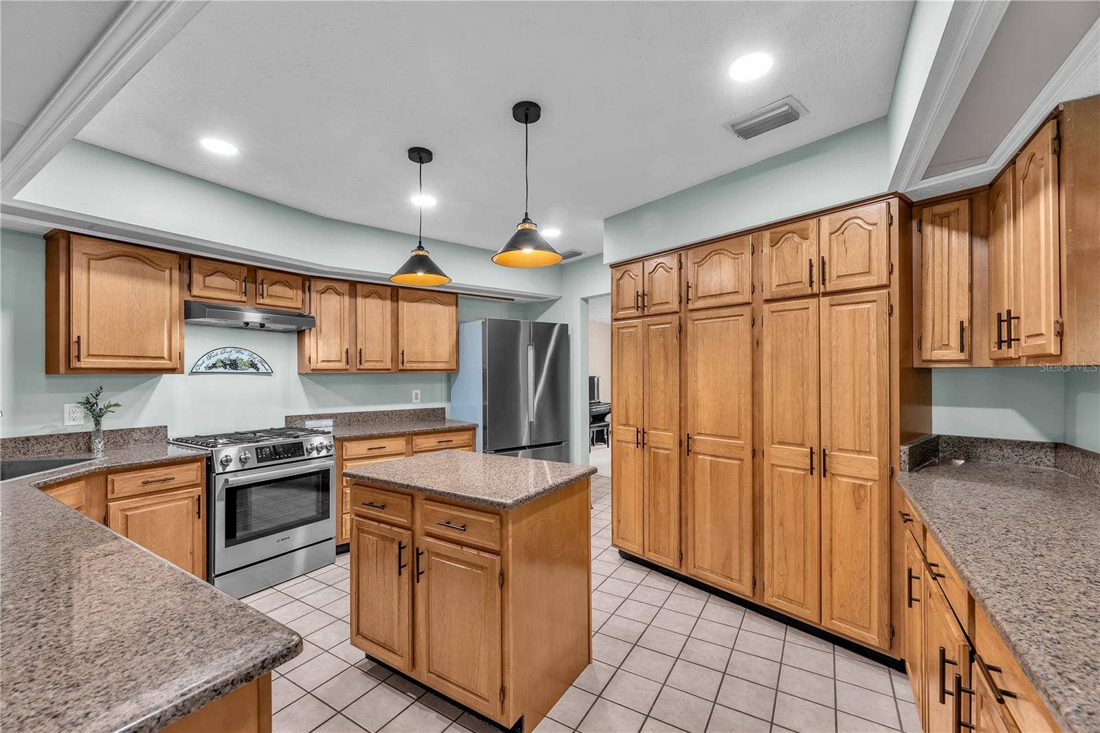 The beautifully appointed kitchen features rich wood cabinetry, gorgeous dark granite countertops, a large cabinet pantry for storage and updated lighting.