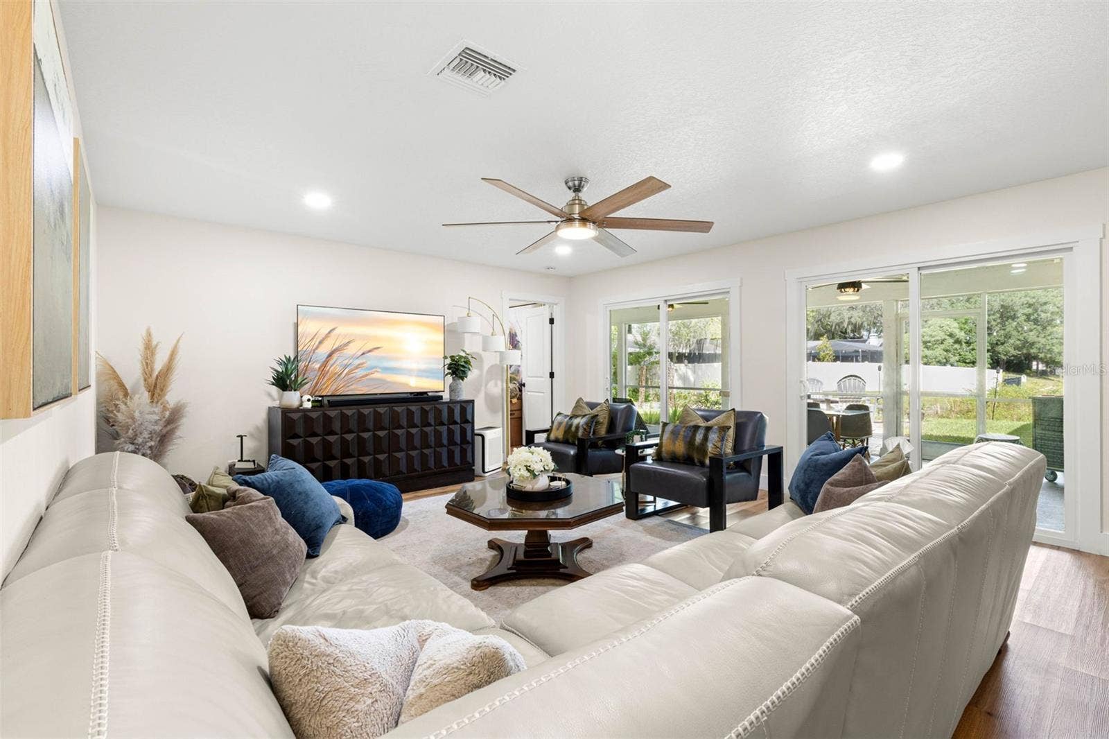 3013 GRAHAM LANE, Tampa, FL 33618 The spacious living room offers plenty of room for comfortable seating and entertaining, with recessed lighting, a contemporary ceiling fan, luxury vinyl flooring, and two sets of sliding glass doors that fill the space with natural light and provide access to the screened porch.