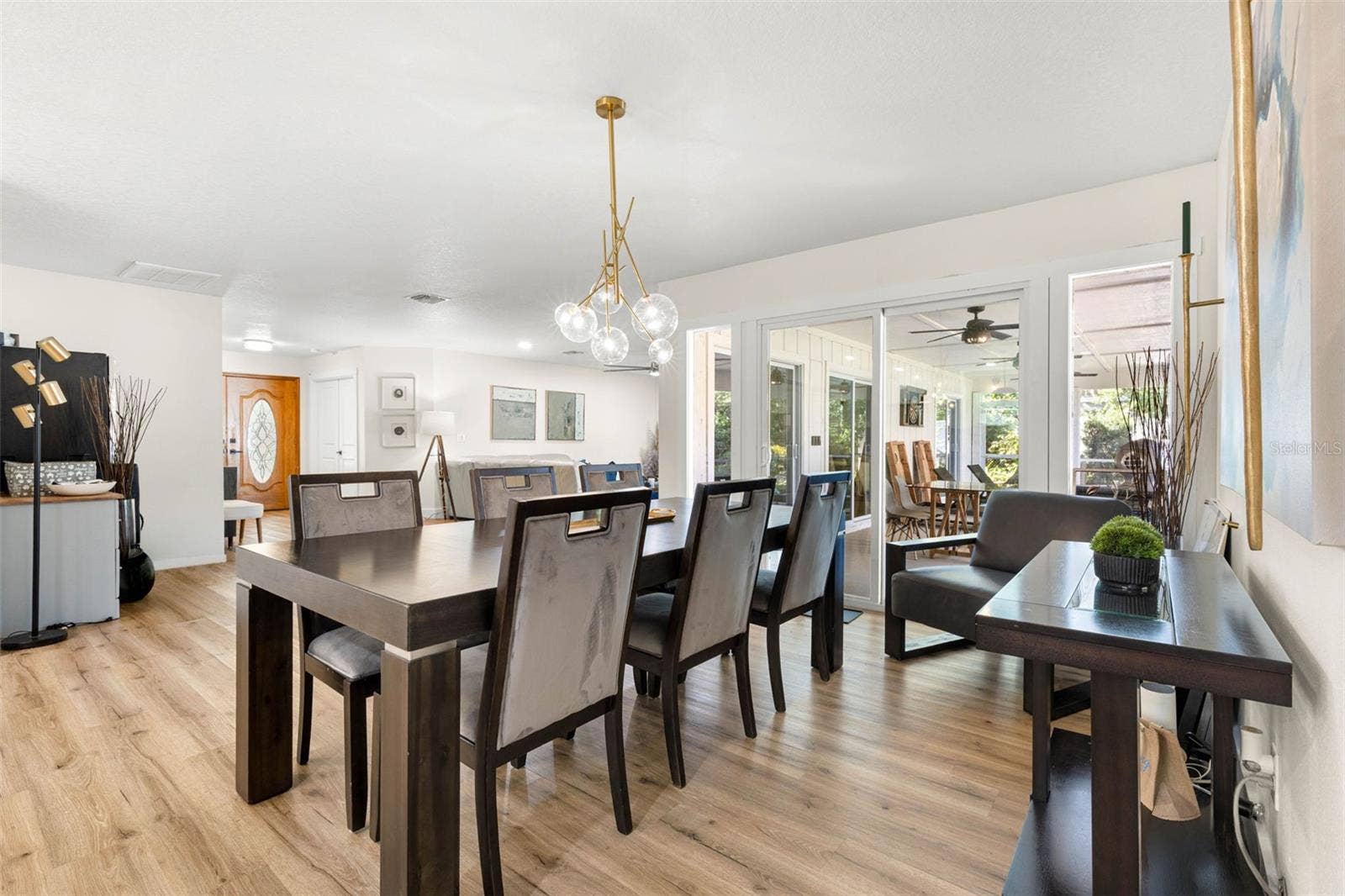 3013 GRAHAM LANE, Tampa, FL 33618 The beautifully appointed dining area features a striking contemporary gold chandelier with glass globe shades, creating an elegant focal point. Generous proportions accommodate a large dining table, while sliding glass doors provide natural light and access to the screened outdoor living area.