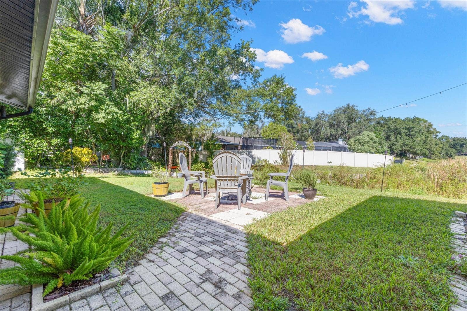 3013 GRAHAM LANE, Tampa, FL 33618 A charming paver walkway leads to an inviting outdoor seating area, perfect for morning coffee, evening conversations, or gathering around a fire pit. Mature trees, lush landscaping, and an open lawn create a peaceful backyard retreat just steps from the pond.