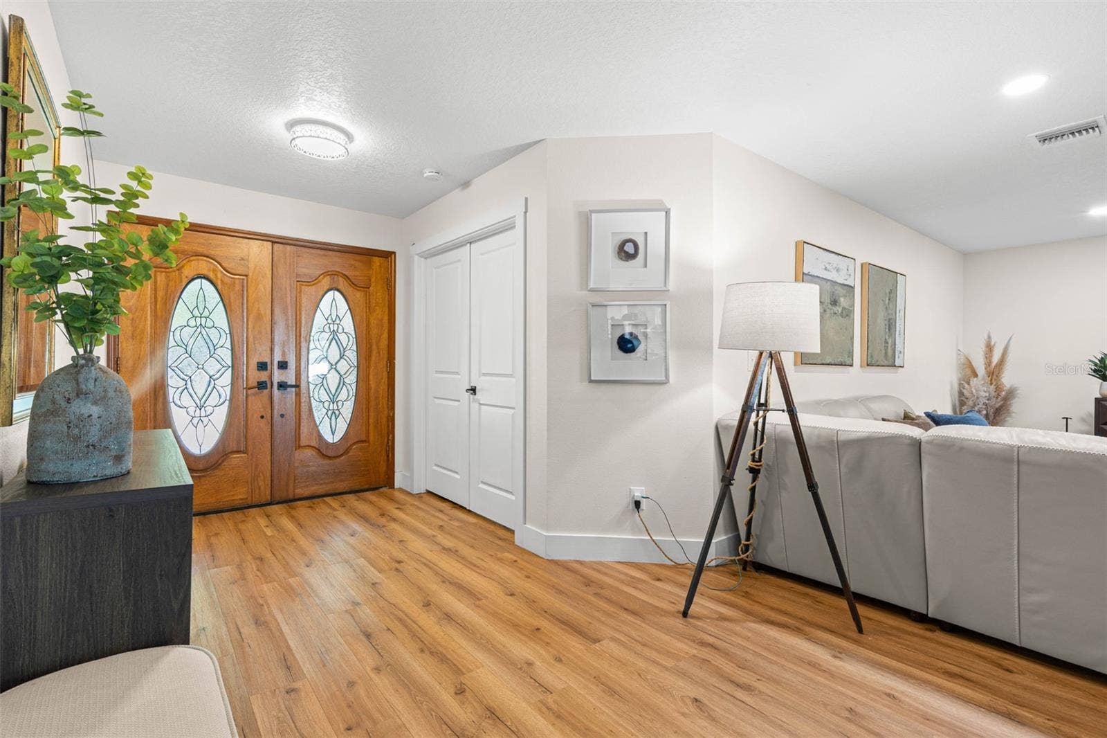 3013 GRAHAM LANE, Tampa, FL 33618 Step inside to a bright, welcoming entryway featuring decorative double doors with leaded-glass inserts, beautiful wood-look luxury vinyl flooring, recessed lighting, and a convenient entry closet. The open layout offers an inviting glimpse into the spacious living area.
