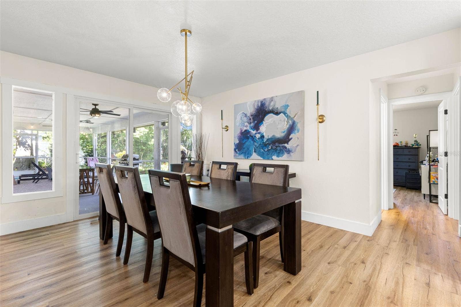 3013 GRAHAM LANE, Tampa, FL 33618 The inviting dining area comfortably accommodates a large table for gatherings and special occasions. Sliding glass doors open to the screened porch, extending the entertaining space outdoors, while an elegant gold chandelier and coordinating wall sconces add a sophisticated touch.