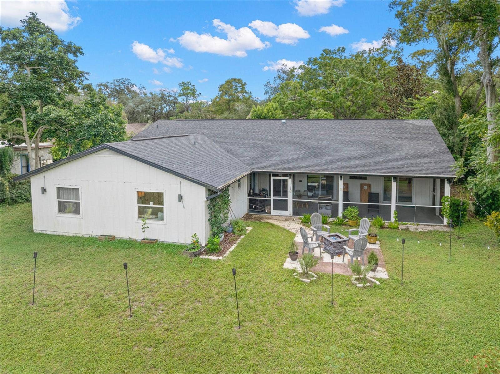 3013 GRAHAM LANE, Tampa, FL 33618 An aerial perspective showcases the home's expansive backyard, mature surrounding trees, and impressive screened porch extending across the rear of the residence. A dedicated patio and fire pit area adds another inviting outdoor gathering space, with plenty of lawn to enjoy.